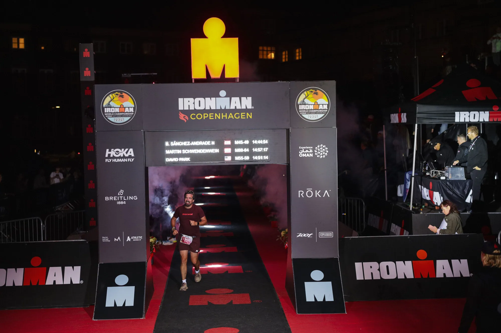 Bruno entering the illuminated IRONMAN Copenhagen finish arch at night